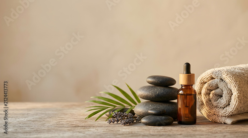 a towel, a bottle of essential oil and some stones on a wooden table