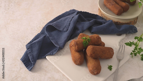 Quadro su tela Homemade savory croquettes served on a white plate with a blue napkin