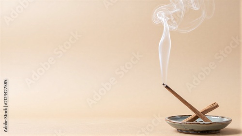 Smoke curls upward from a lit incense stick in a small ceramic holder.