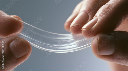 A clear, stretchy gel or silicone material being elongated between four fingers illustrates its flexibility and strength for medical, cosmetic, or industrial uses.