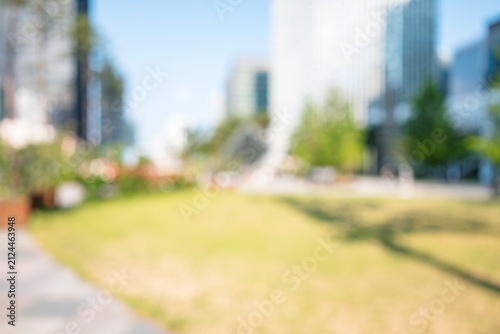 Abstract blurred modern urban eco park background with green lawn and skyscrapers