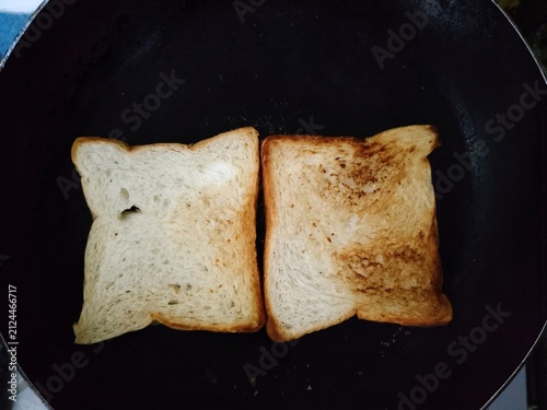Two Slices of Bread Toasting in a Black Pan.