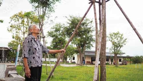 Happy Asian senior woman sitting alone outdoors at cafe table. Retirement freedom and relaxed elderly lifestyle concept.