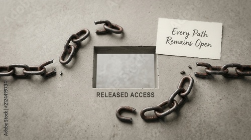 Broken metal chains lying on grey concrete surface near a rectangular hole labeled released access with an inspirational note saying every path remains open representing freedom and new