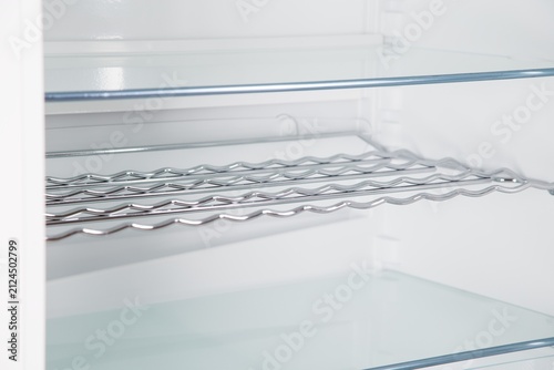 Empty Refrigerator Interior with Chrome Bottle Rack and Glass Shelves
