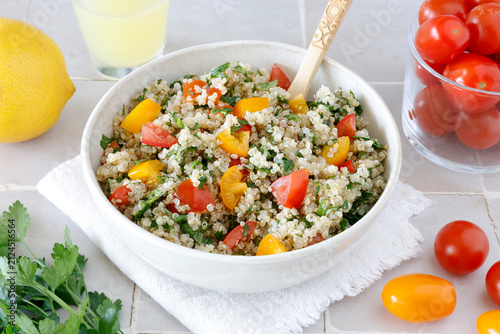 Close-up of a bowl of homemade tabbouleh made with quinoa, tomatoes, mint, and parsley.
