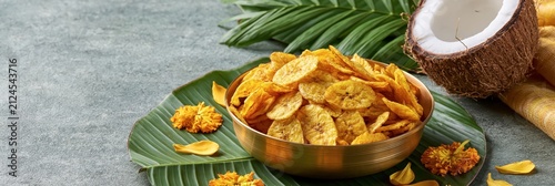 Bowl of crispy banana chips served on a banana leaf with coconut and flowers, onam festival banner realistic banner
