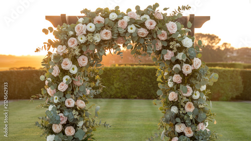 Elegant flower arch at sunset in wedding garden, glowing ambiance