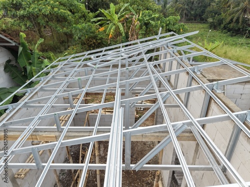 Metal Roof Trusses Installation on Building Construction Site with Green Surroundings