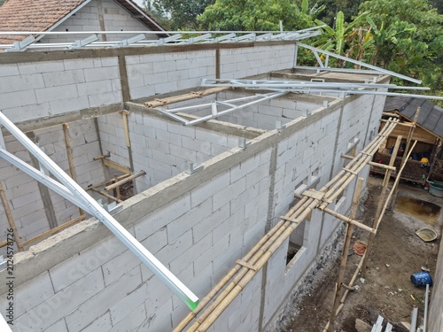 Construction Site: Concrete Block Building with Metal Roof Frames and Bamboo Scaffolding