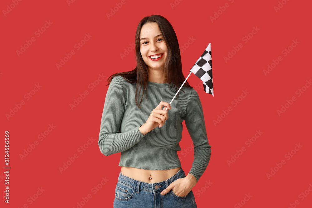 Fototapeta premium Beautiful young woman with racing flag on red background