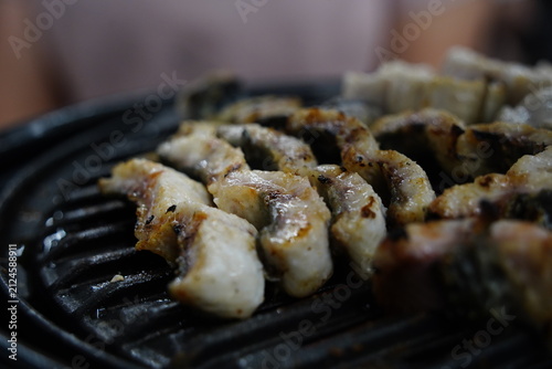 Fresh eels grilling on a charcoal brazier grill close up