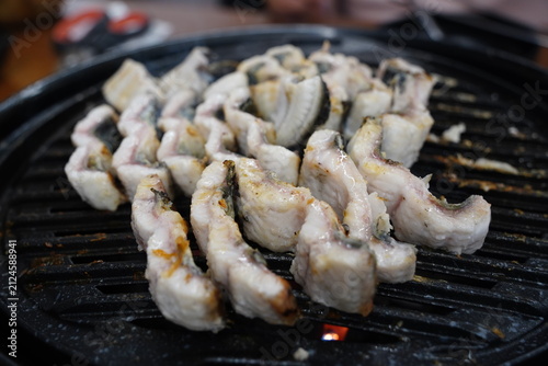 Fresh eels grilling on a charcoal brazier grill close up