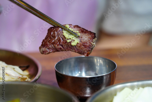 Holding a piece of juicy grilled Korean beef Hanwoo with chopsticks close up