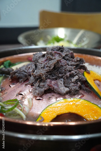 Sliced beef Bulgogi hot pot boiling on a traditional bronze pan with vegetables