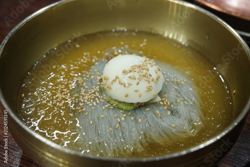 Chilled buckwheat noodles Mul-Naengmyeon with ice broth and boiled egg in brass bowl
