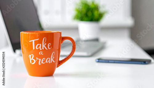Orange coffee mug with Take a Break text on office desk