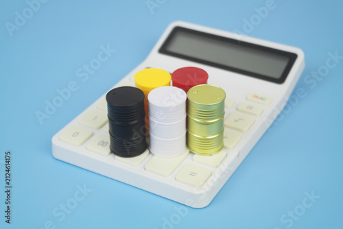 Different crude oil barrels on calculator on blue background. Crude oil price concept.