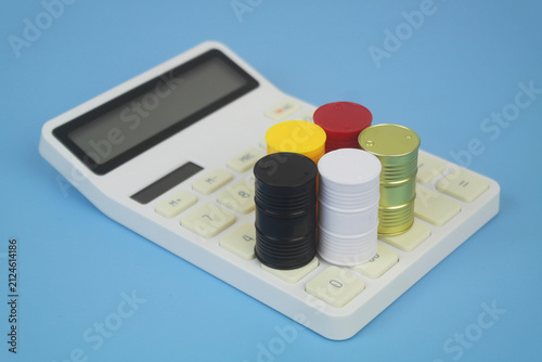 Different crude oil barrels on calculator on blue background. Crude oil price concept.