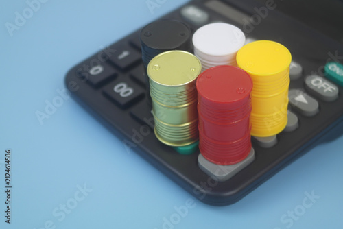 Different crude oil barrels on calculator on blue background. Crude oil price concept.