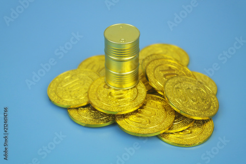 Golden crude oil barrel on gold coins on blue background. Oil price concept.