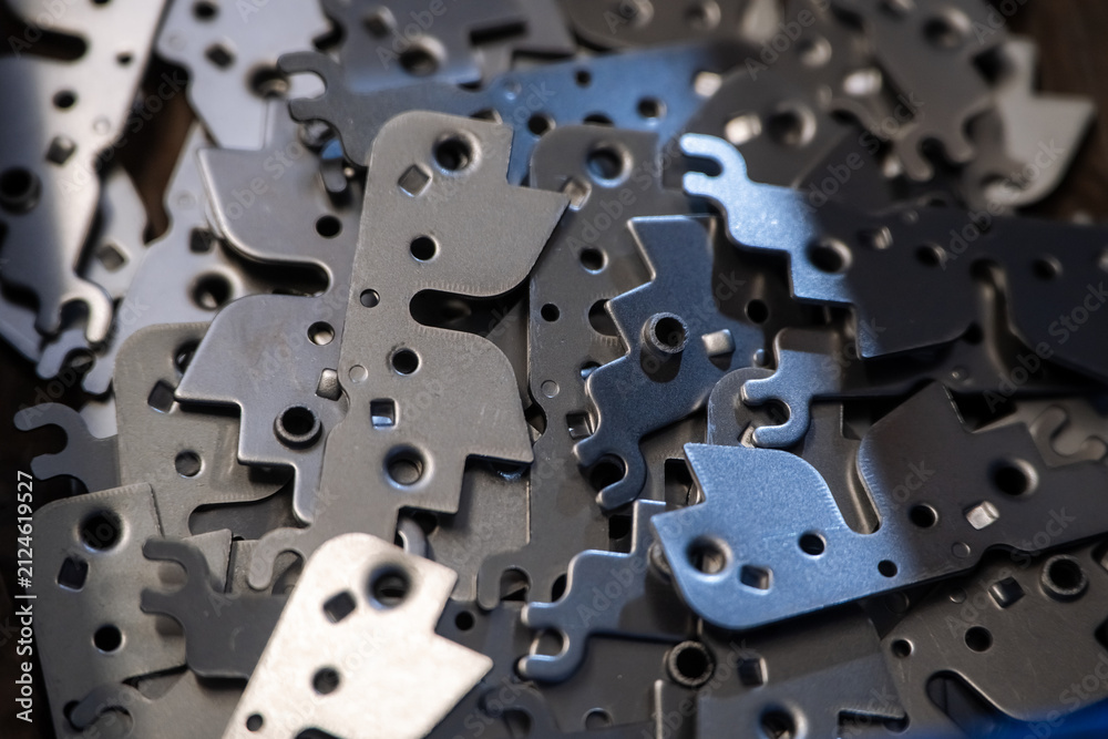 Obraz premium Scattered metal components feature irregular shapes and holes. Close-up view shows various sizes of parts. Each piece has cutouts and mounting holes