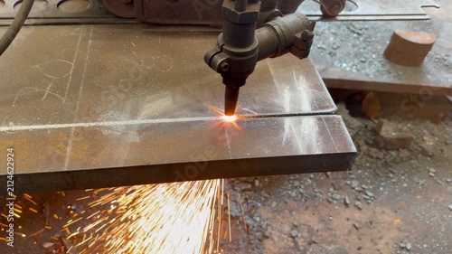 Oxy-fuel gas cutting machine cutting thick steel plate with bright sparks in metal fabrication workshop