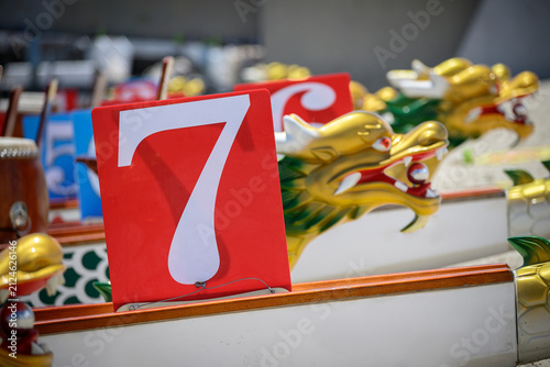 A dragon boat marked with the number 7 is lined up alongside other racing boats before a competition or practice session
