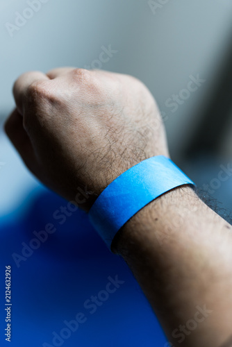 Hand with blue paper bracelet. Wristband for admission to a concert or entertainment center