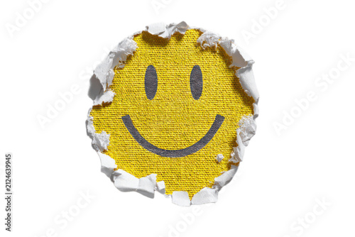 Smiley face emoji revealed through torn white paper hole