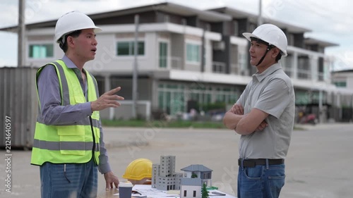 Architect and Civil Engineer Discussing Building Plans with Architectural Models and Blueprint on Worktable