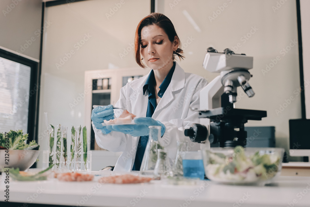 Fototapeta premium Scientists in lab coats work with plants in a modern lab, focusing on research and experimentation under bright, sterile conditions.
