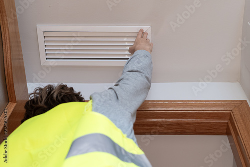 Professional wearing a reflective vest inspecting a ceiling air vent, checking the home's ventilation and hvac system during a thorough property assessment