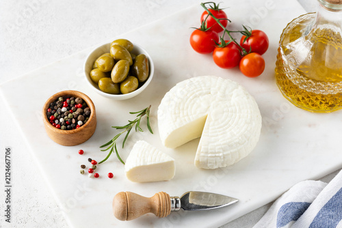 White cheese, olives, tomatoes and olive oil on marble serving board. Cheese plate