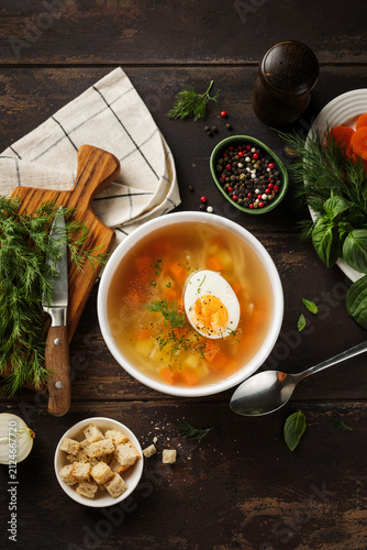 Chicken soup with boiled egg and croutons in a bowl. Chicken broth. Dinner rustic composition