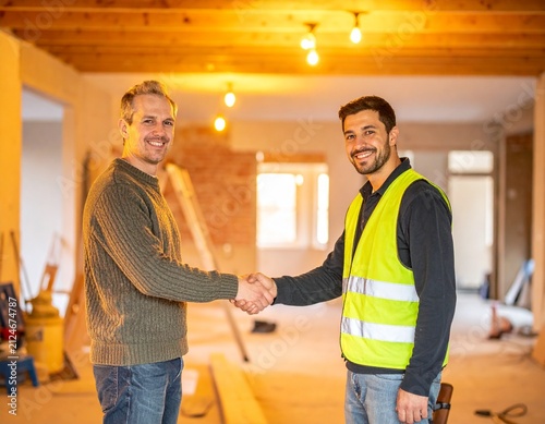 Homeowner Happily Shakes Hands with Construction Worker Amid Golden Lit Renovation Process Showcasing a Cheerful and Collaborative Mood for the Home Improvement Project