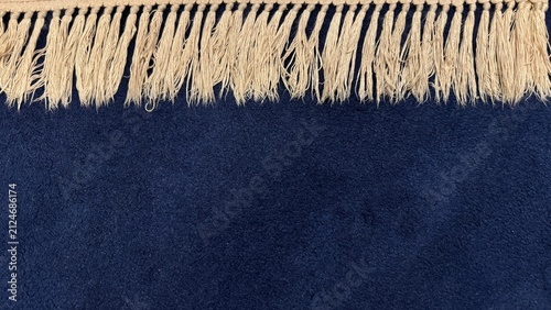 Close-up high-quality photo of the fringe edge on a soft, dark blue velvet carpet. Perfect for textile textures, home decor products, or interior design concepts. Minimalist and elegant look