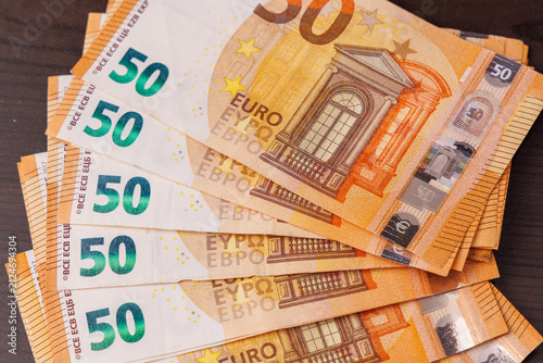 Fifty euro banknotes in a fan shape on a dark wooden table, overhead top view showing wealth, business finance, and savings