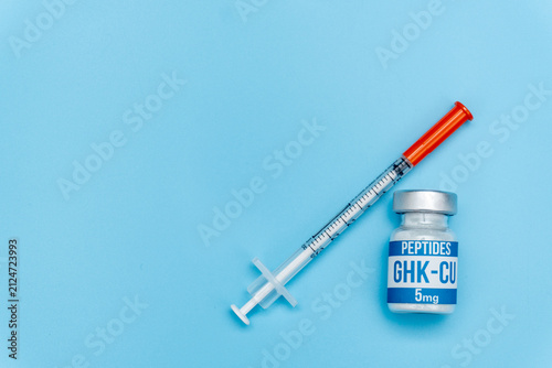 GHK-CU Peptide Vial with Insulin Syringe on Blue Background, Flat Lay