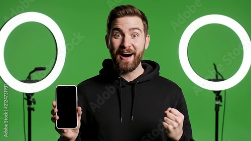 Influencer Celebrating Follower Milestone Holding Smartphone Smiling Against Green Screen Background