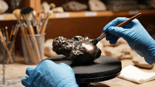 Latina Female Restoration Intern Cleaning A Bronze Sculpture in An Art Studio Environment Focusing On Meticulous Craftsmanship and Preservation Techniques