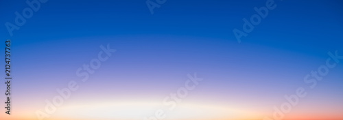 The transitional colors of the sky at sunrise. The sun is rising against a blue sky.