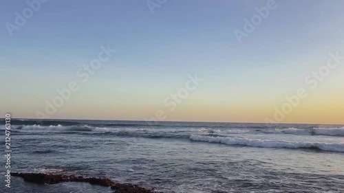 Calm Sea Waves Flowing Across Rocky Shore at Golden Hour