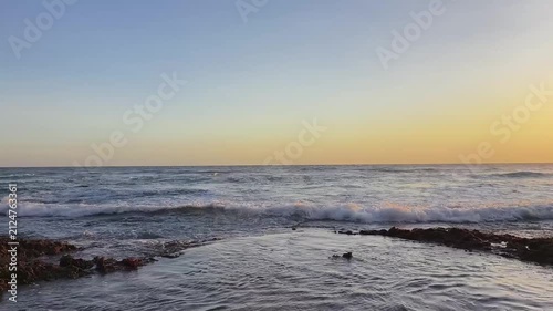Calm Sea Waves Flowing Across Rocky Shore at Golden Hour