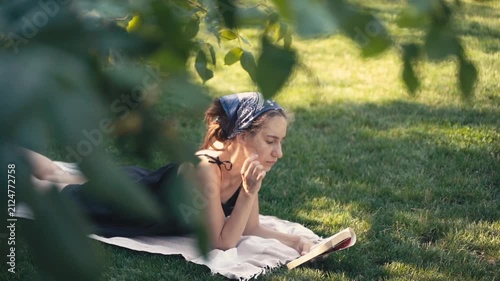 Young woman reading a book on the grass in a park