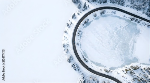 Aerial view of a car driving on a curved road by a frozen lake in winter