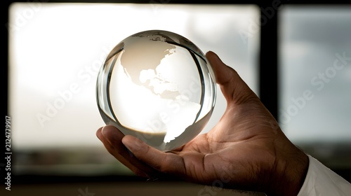 Glowing Glass Globe with Faint Continents in Hand against Bright Window