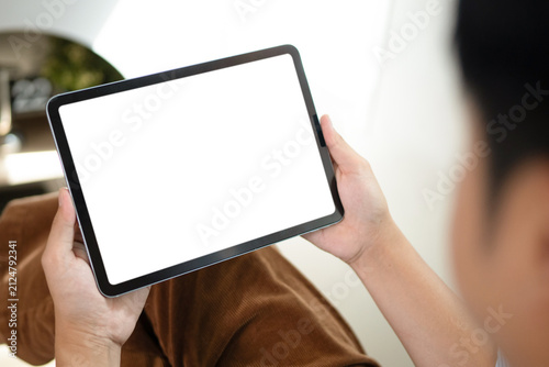 Over the shoulder view of a man holding a tablet with an empty white screen, perfect for app UI mockup and digital content placement