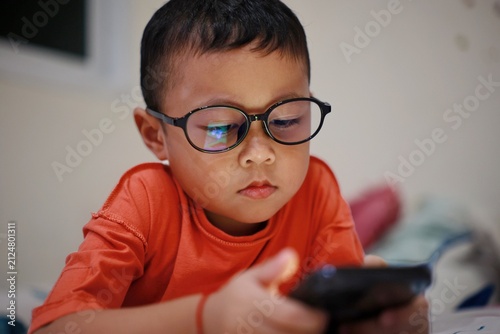 Child using smartphone at night, The little boy is using a smartphone at home at night. Closeup of a little boy face in night, using phone, technology concept