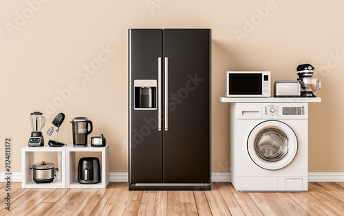 Modern refrigerator and other household appliances near beige wall indoors